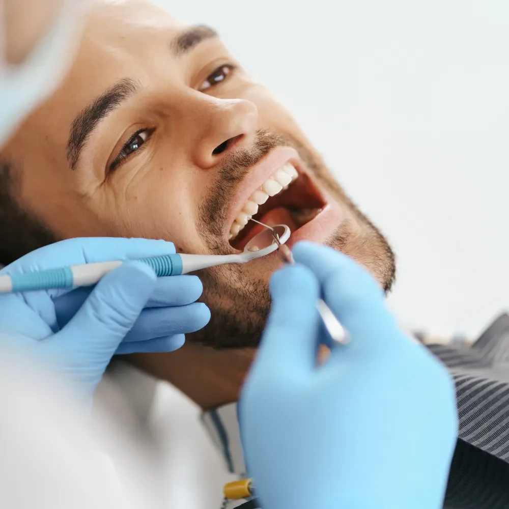 Dentist performing professional teeth cleaning on a male patient during a dental checkup in a clinic
