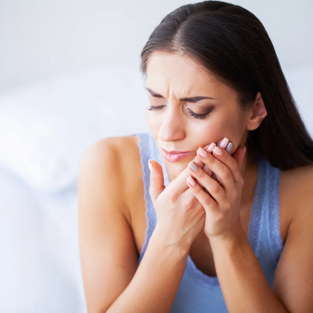 Woman experiencing tooth pain that may require dental restoration treatment