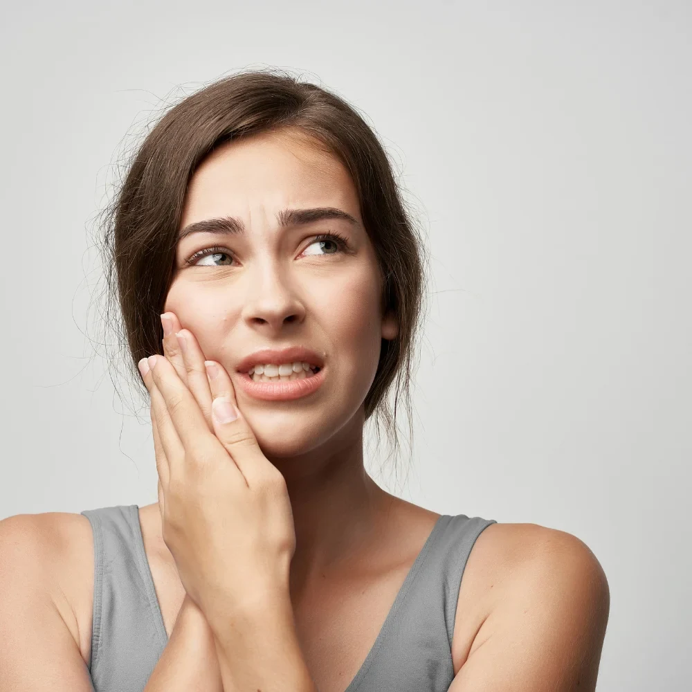 Woman holding jaw due to severe tooth pain from possible infection