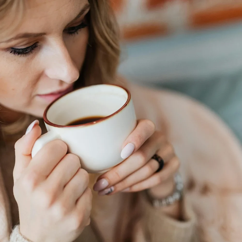 Woman drinking coffee which can cause teeth staining over time